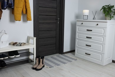 Photo of Shoe storage bench and chest of drawers near white wall in hallway. Interior design