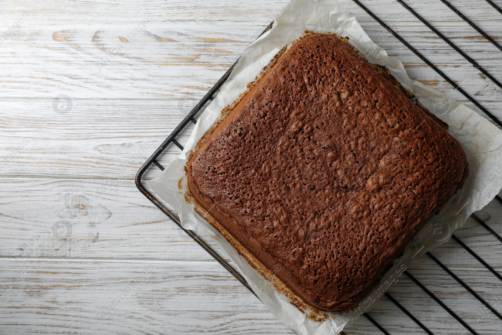 Photo of Homemade chocolate sponge cake on white wooden table, top view. Space for text