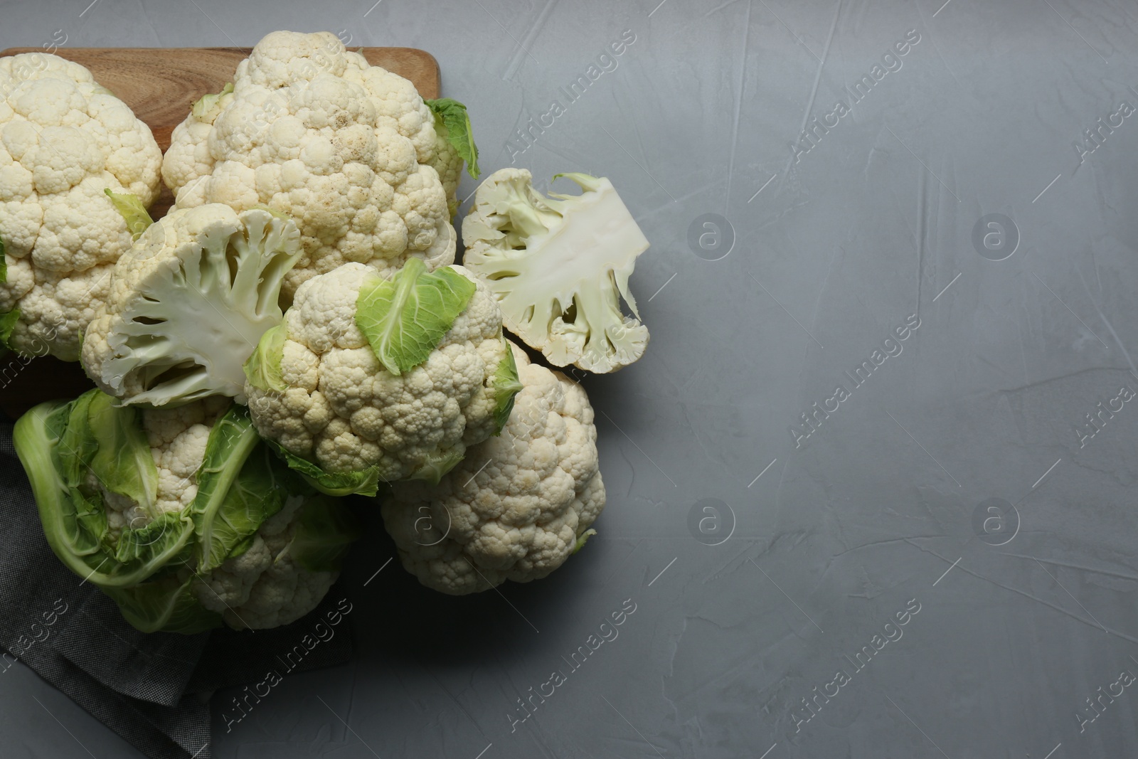 Photo of Fresh whole and cut cauliflowers on light grey table, top view. Space for text