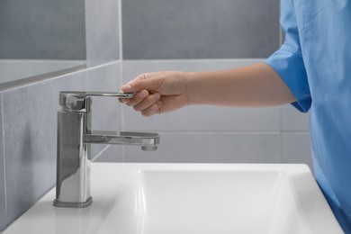 Photo of Doctor opening tap water in bathroom, closeup