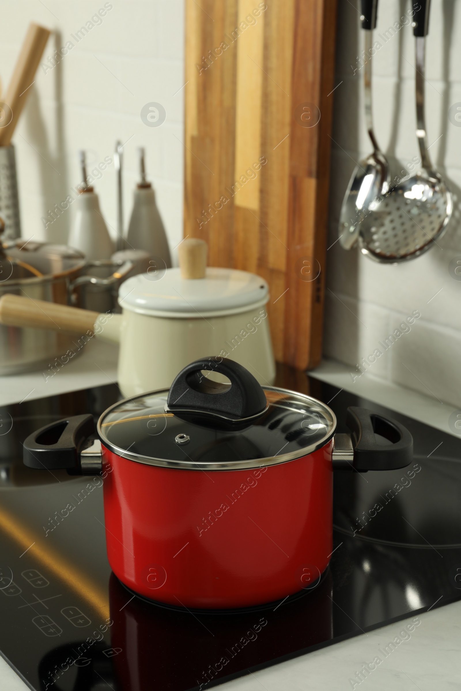 Photo of Red pot on electric stove in kitchen. Cooking utensil