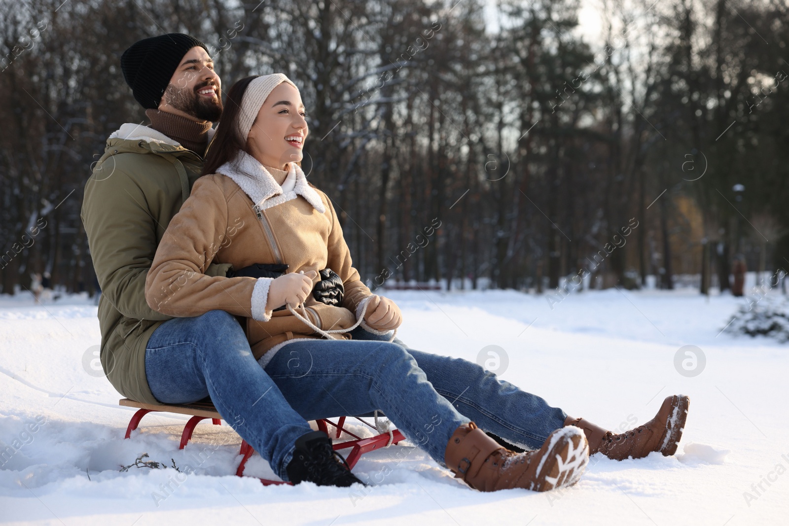 Photo of Happy young couple sledding outdoors on winter day