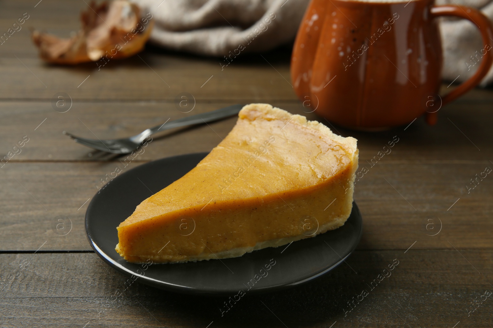 Photo of Piece of delicious pumpkin pie on wooden table, closeup