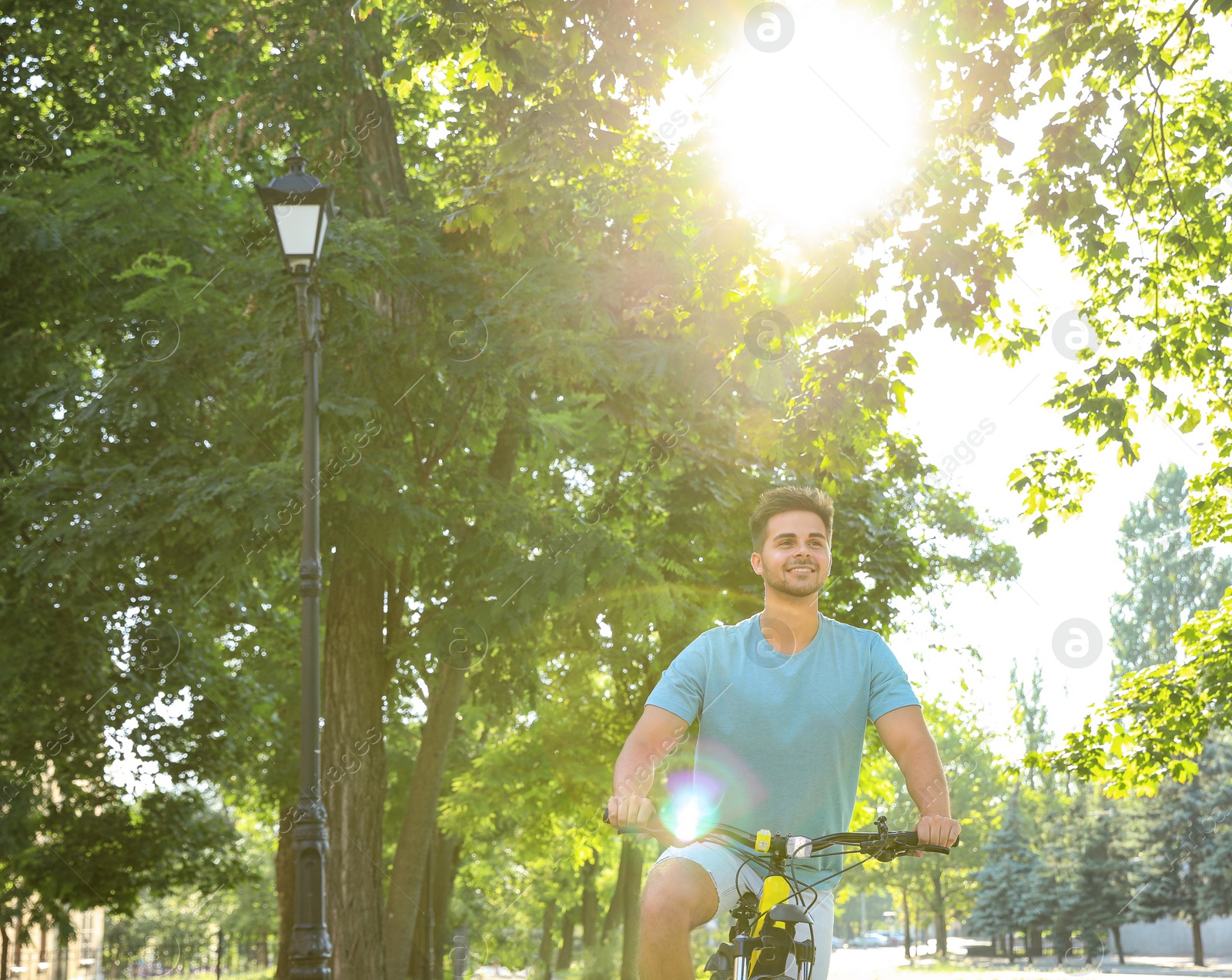 Photo of Handsome young man riding bicycle on city street, low angle view