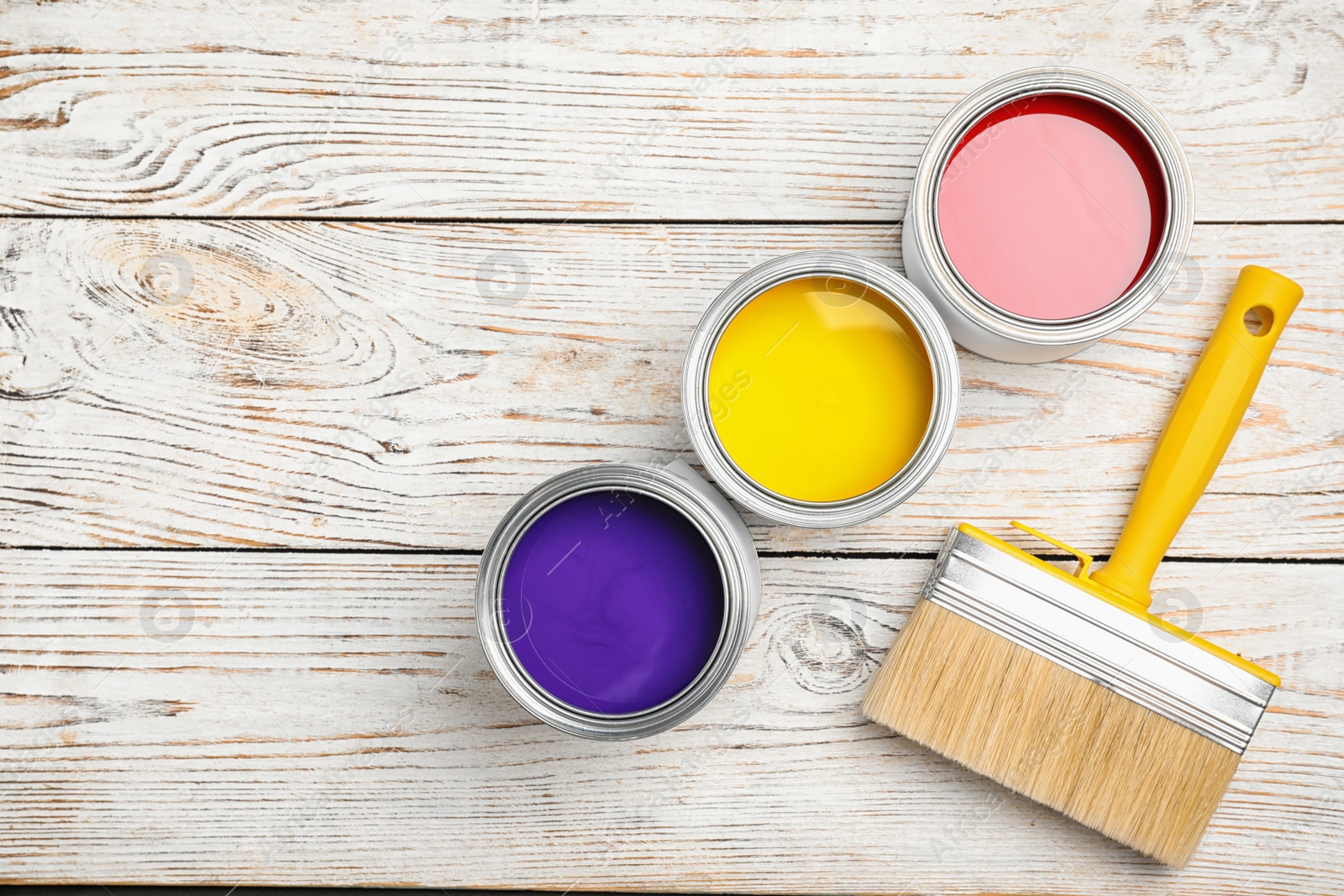 Photo of Open cans with paint and brush on white wooden background, flat lay. Space for text