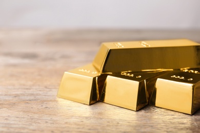 Photo of Precious shiny gold bars on wooden table