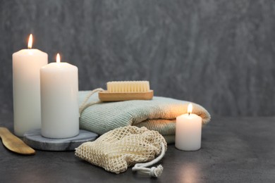 Photo of Composition with different spa products and burning candles on grey table, space for text