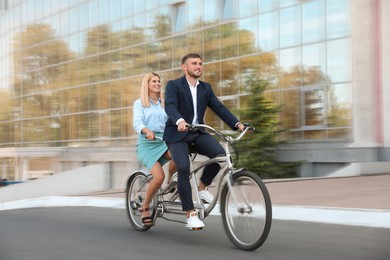 Image of Couple riding tandem bike on city street, motion blur effect