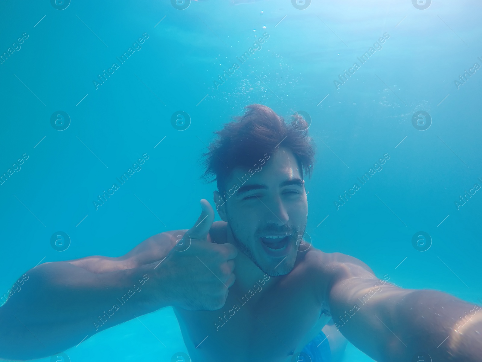 Photo of Handsome young man swimming in pool, underwater view