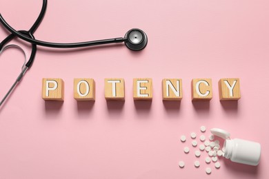 Photo of Word Potency made of wooden cubes, stethoscope and pills on light pink background, flat lay