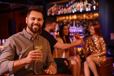 Friends spending time together in bar. Handsome man with fresh alcoholic cocktail at table, space for text