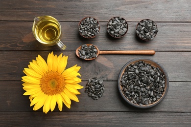 Photo of Flat lay composition with sunflower seeds and flower on wooden table