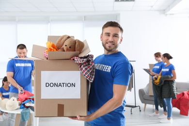 Photo of Male volunteer holding box with donations indoors