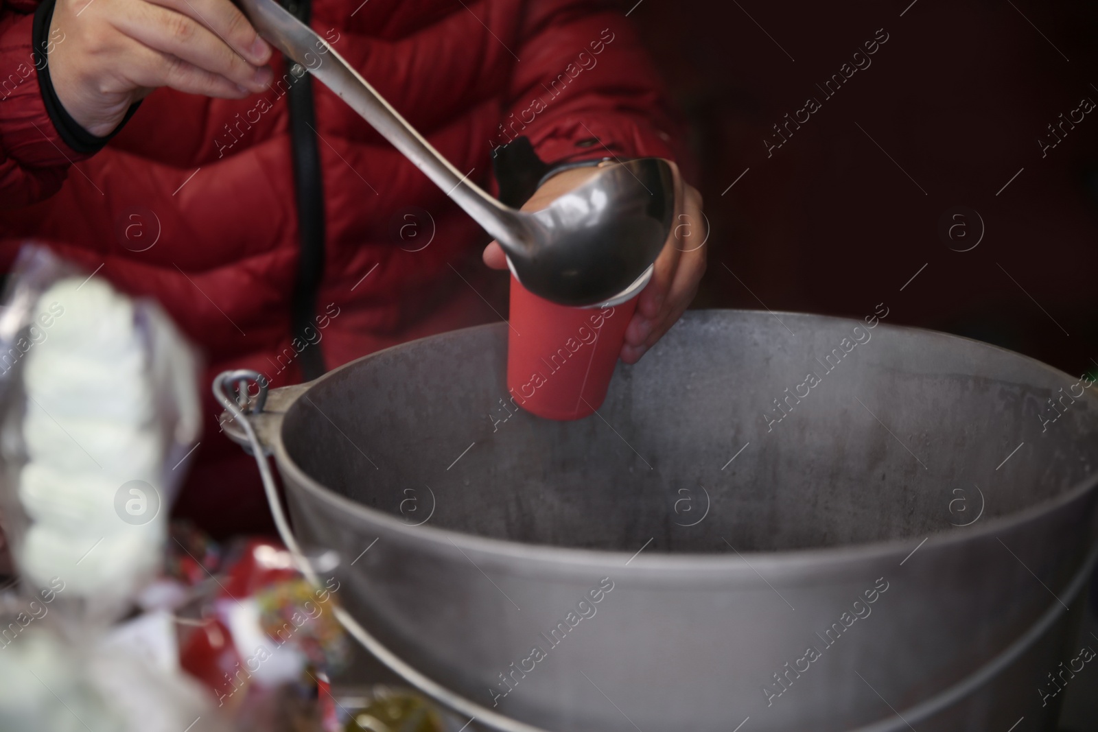 Photo of Seller pouring hot mulled wine into cup, closeup