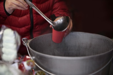 Photo of Seller pouring hot mulled wine into cup, closeup