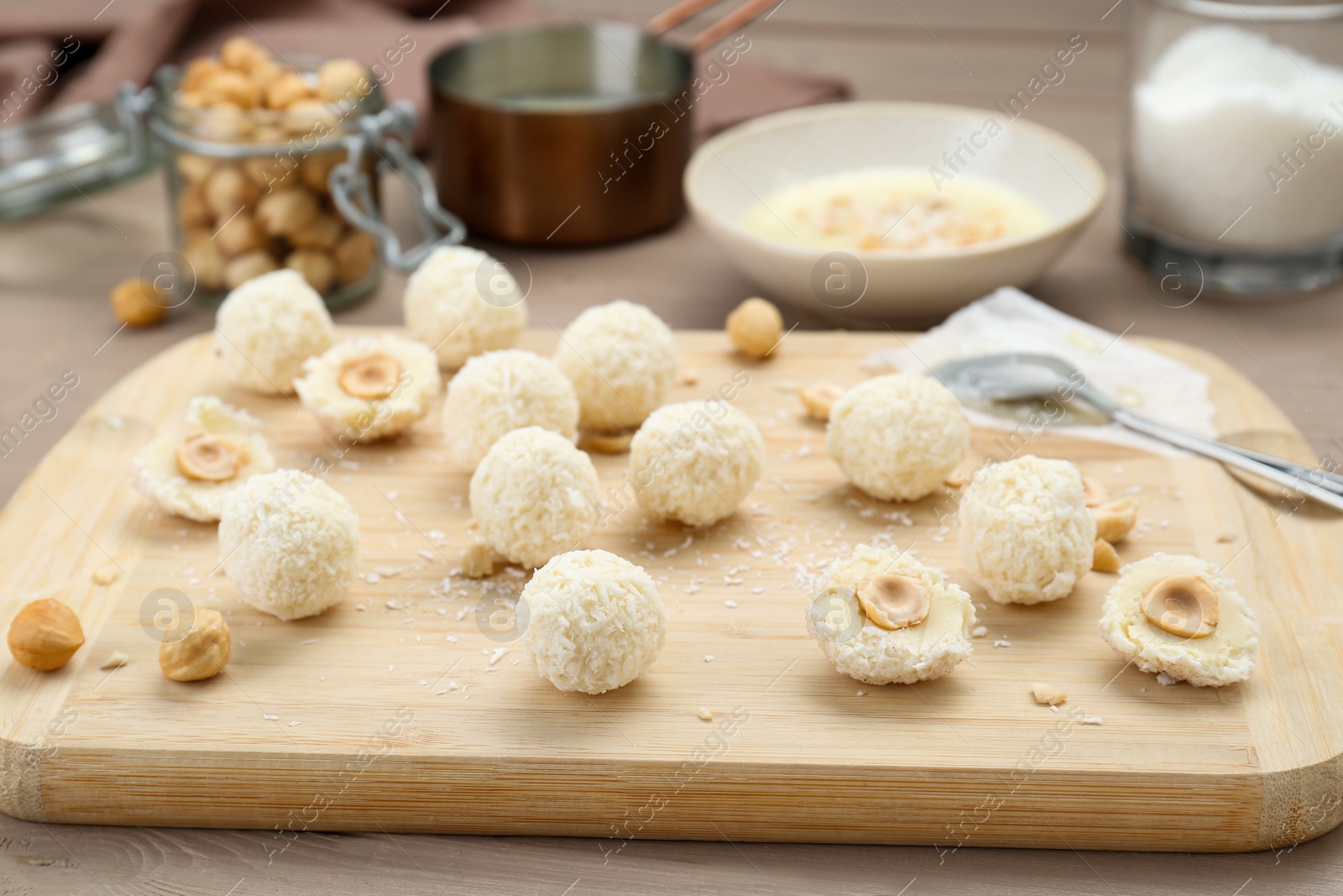 Photo of Delicious candies with coconut flakes and hazelnut on wooden table