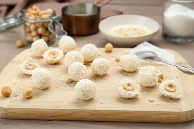 Photo of Delicious candies with coconut flakes and hazelnut on wooden table