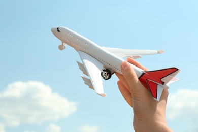 Photo of Woman holding toy airplane against blue sky, closeup