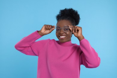 Photo of Portrait of beautiful young woman in eyeglasses on light blue background