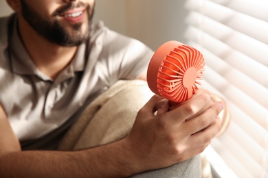 Photo of Man enjoying air flow from portable fan at home, closeup. Summer heat