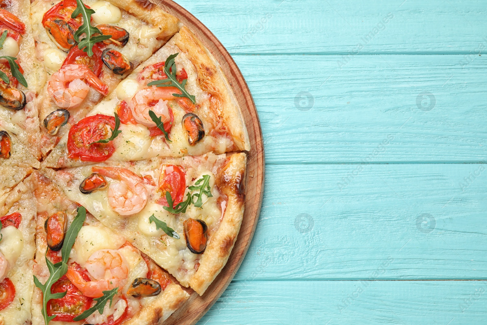 Photo of Delicious seafood pizza on light blue wooden table, top view. Space for text