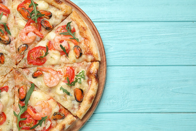 Delicious seafood pizza on light blue wooden table, top view. Space for text