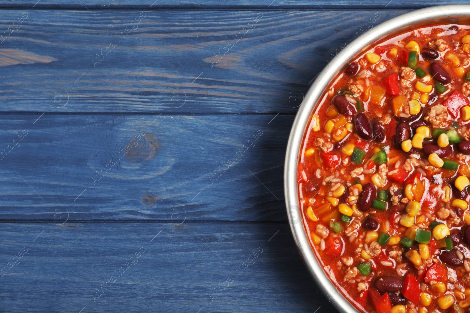 Photo of Frying pan with chili con carne on wooden background, top view. Space for text