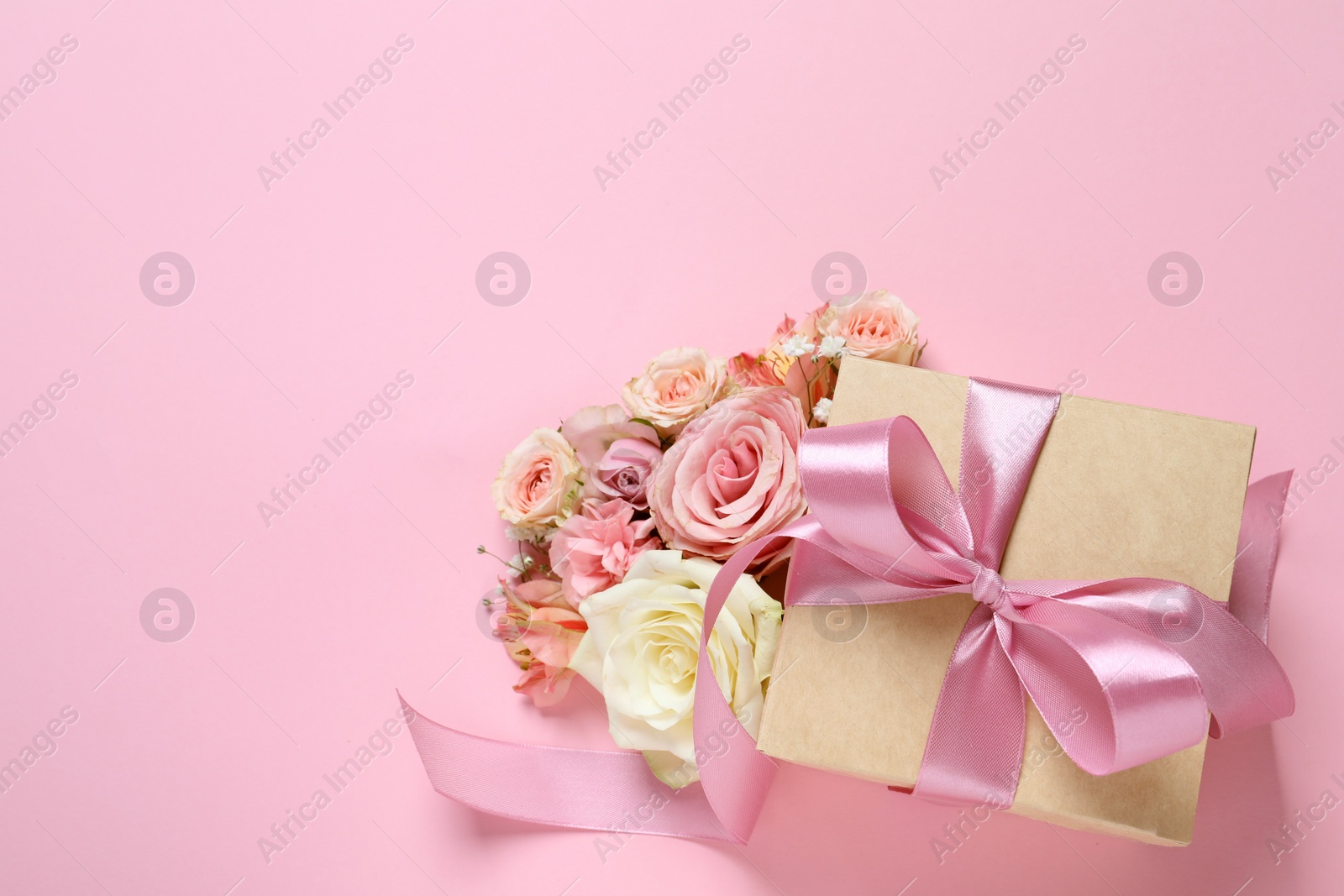 Photo of Gift box and beautiful flowers on pink background, flat lay. Space for text