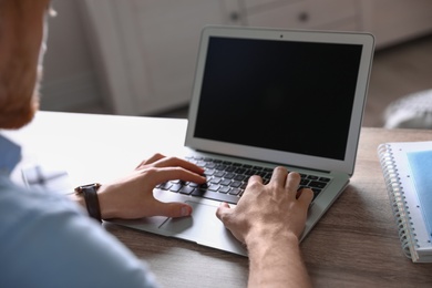 Photo of Man using laptop at table indoors, closeup. Space for text