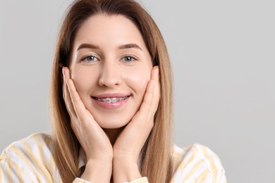 Portrait of smiling woman with dental braces on grey background