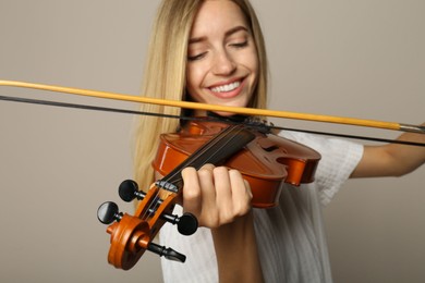 Photo of Beautiful woman playing violin on beige background, closeup