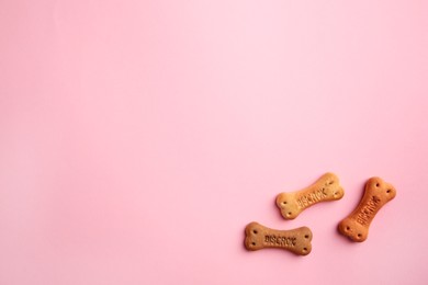 Photo of Bone shaped dog cookies on pink background, flat lay. Space for text