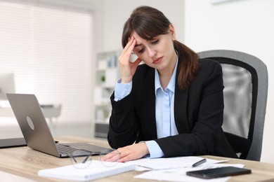 Photo of Overwhelmed woman suffering at table in office