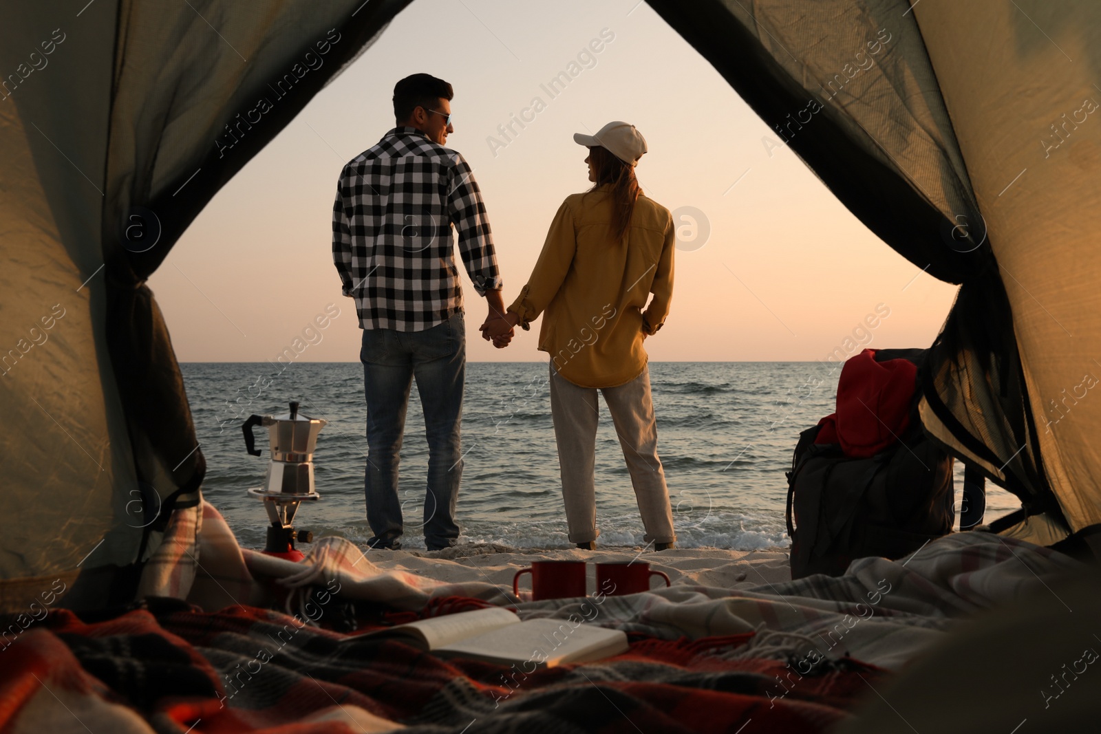 Photo of Couple near sea at sunset, view from camping tent