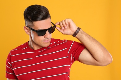 Photo of Handsome man wearing sunglasses on yellow background