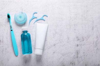 Photo of Flat lay composition with dental floss and different teeth care products on light grey textured table. Space for text