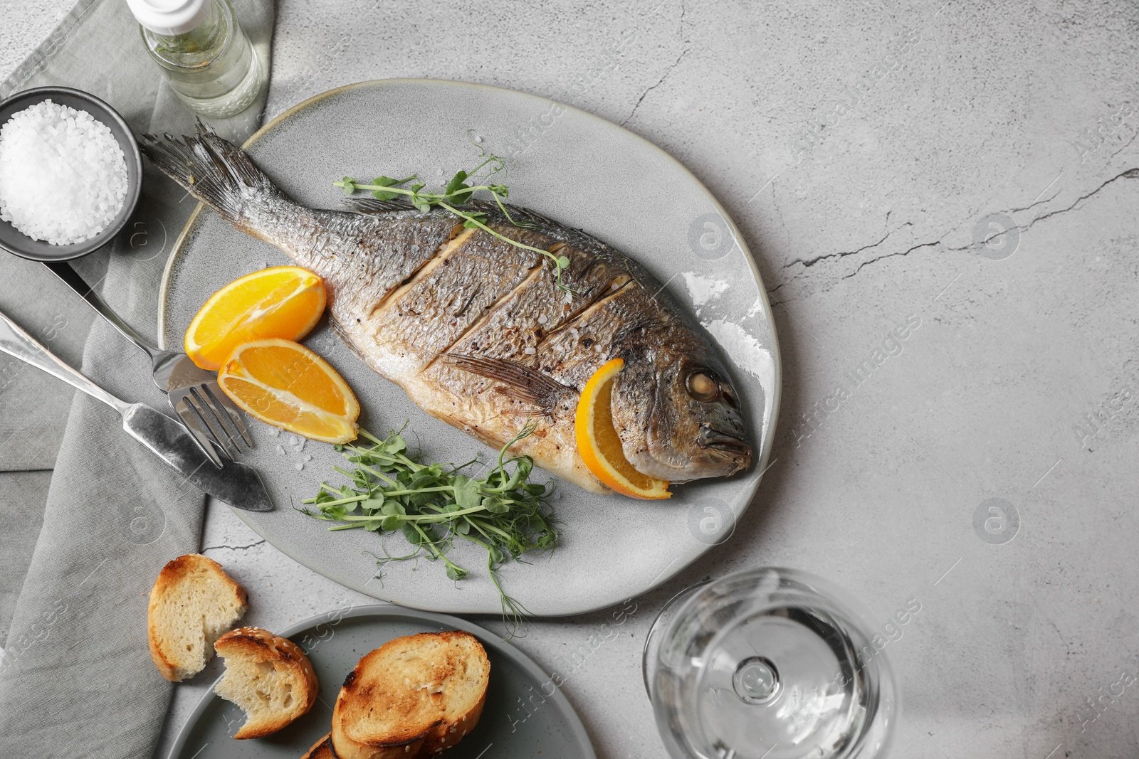 Photo of Seafood. Delicious baked fish served on grey textured table, flat lay with space for text