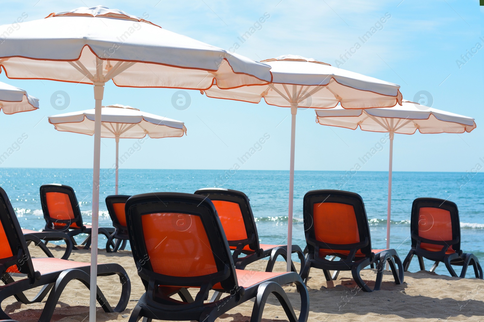 Photo of Empty sunbeds and beach umbrellas at tropical resort on sunny day