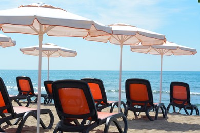 Photo of Empty sunbeds and beach umbrellas at tropical resort on sunny day