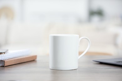 Photo of White ceramic mug and notebooks on wooden table indoors. Space for text