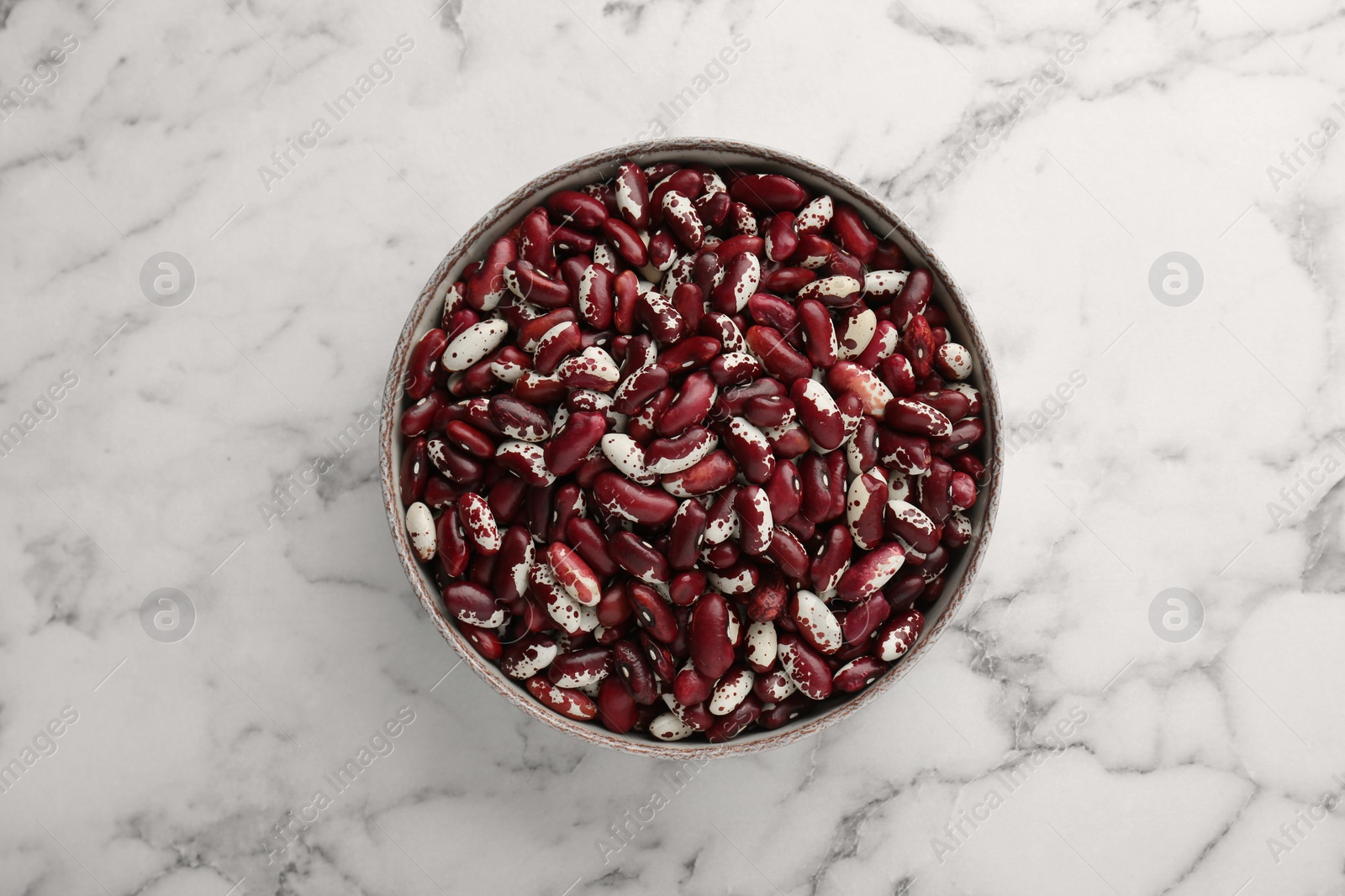 Photo of Bowl with dry kidney beans on white marble table, top view