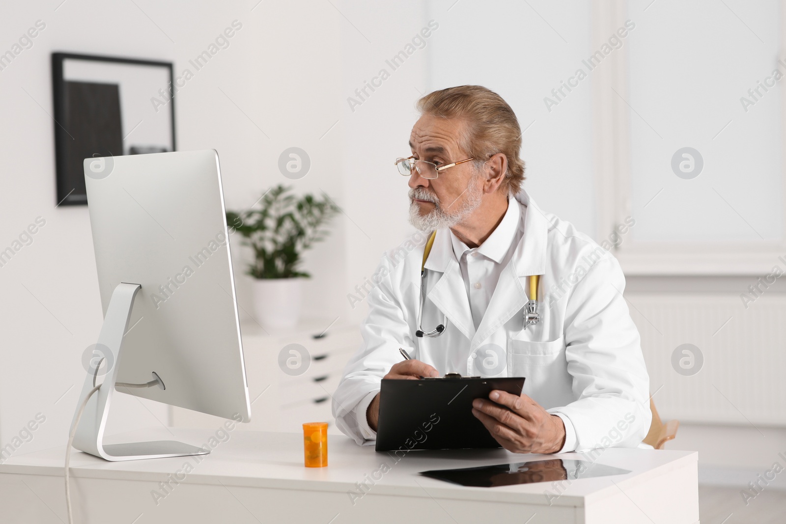 Photo of Doctor filling patient's medical card at table in clinic