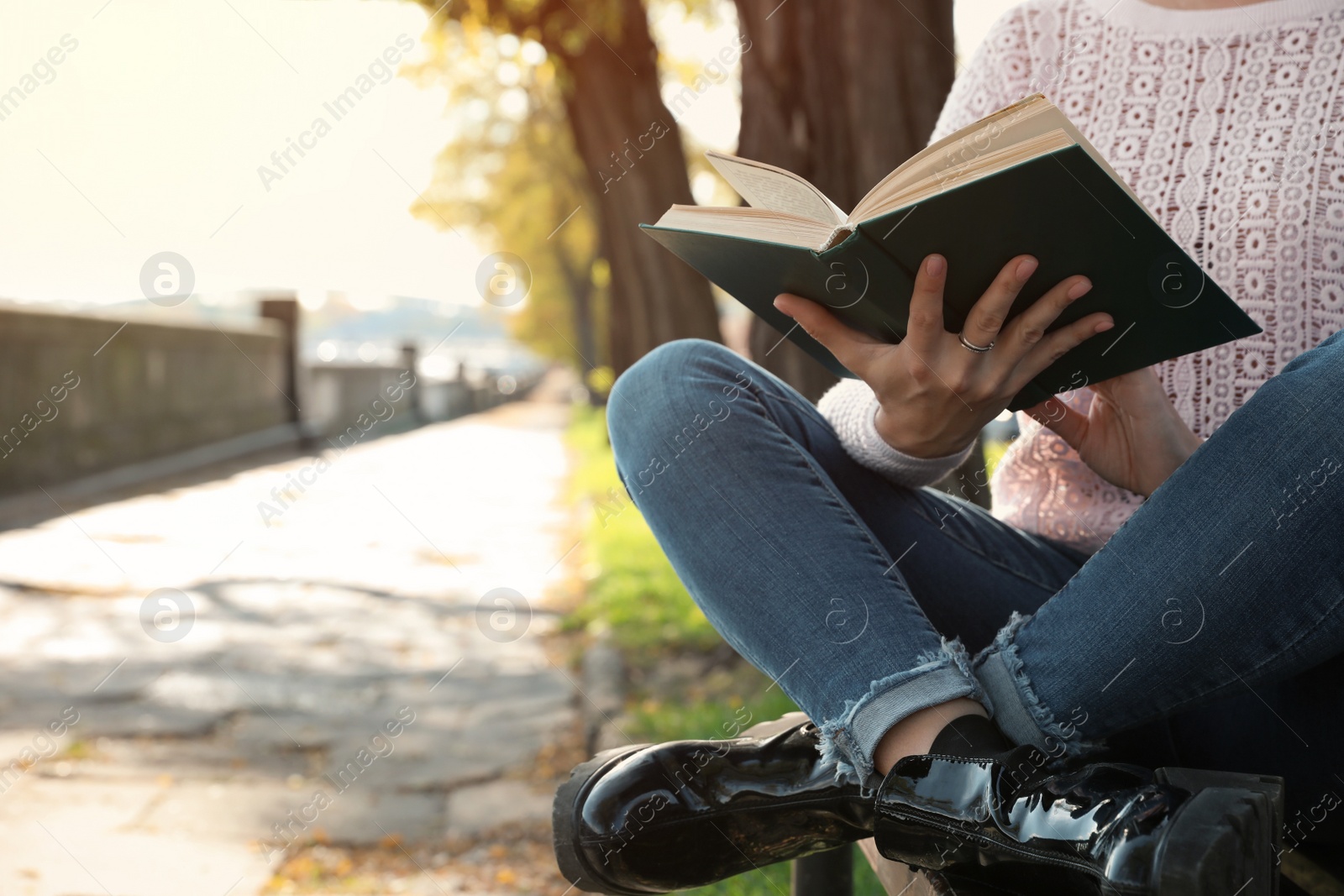 Photo of Woman reading book in sunny park, closeup