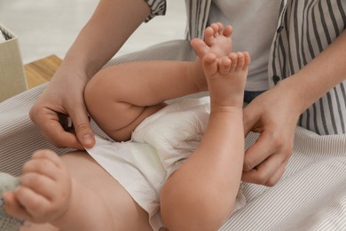 Mother changing baby's diaper on table at home, closeup