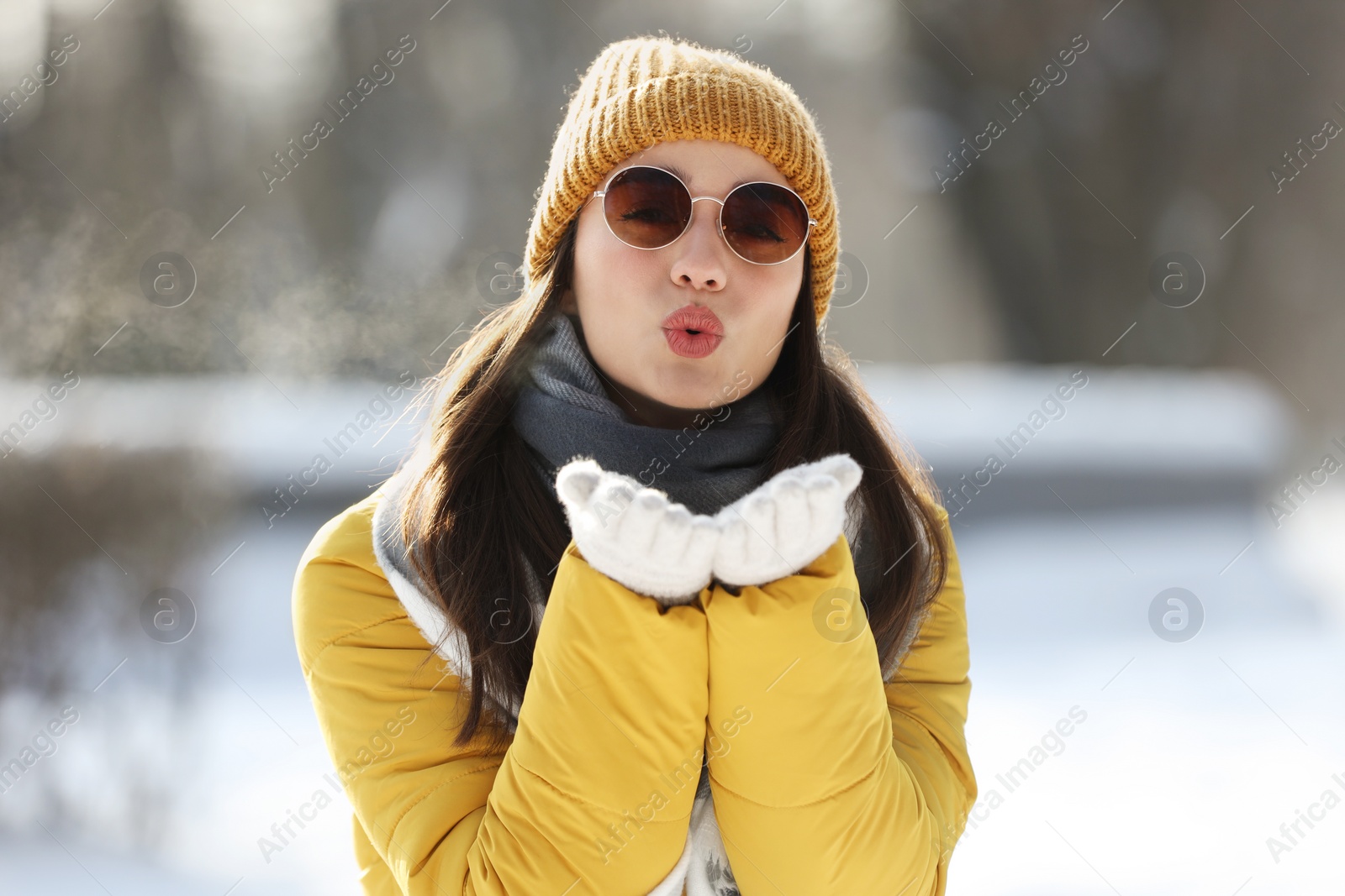 Photo of Beautiful young woman with sunglasses blowing kiss on winter day outdoors