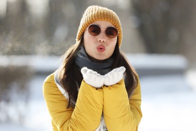 Photo of Beautiful young woman with sunglasses blowing kiss on winter day outdoors