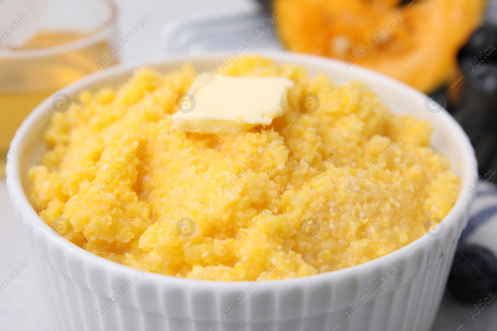 Photo of Tasty cornmeal with butter in bowl on table, closeup