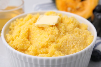 Photo of Tasty cornmeal with butter in bowl on table, closeup