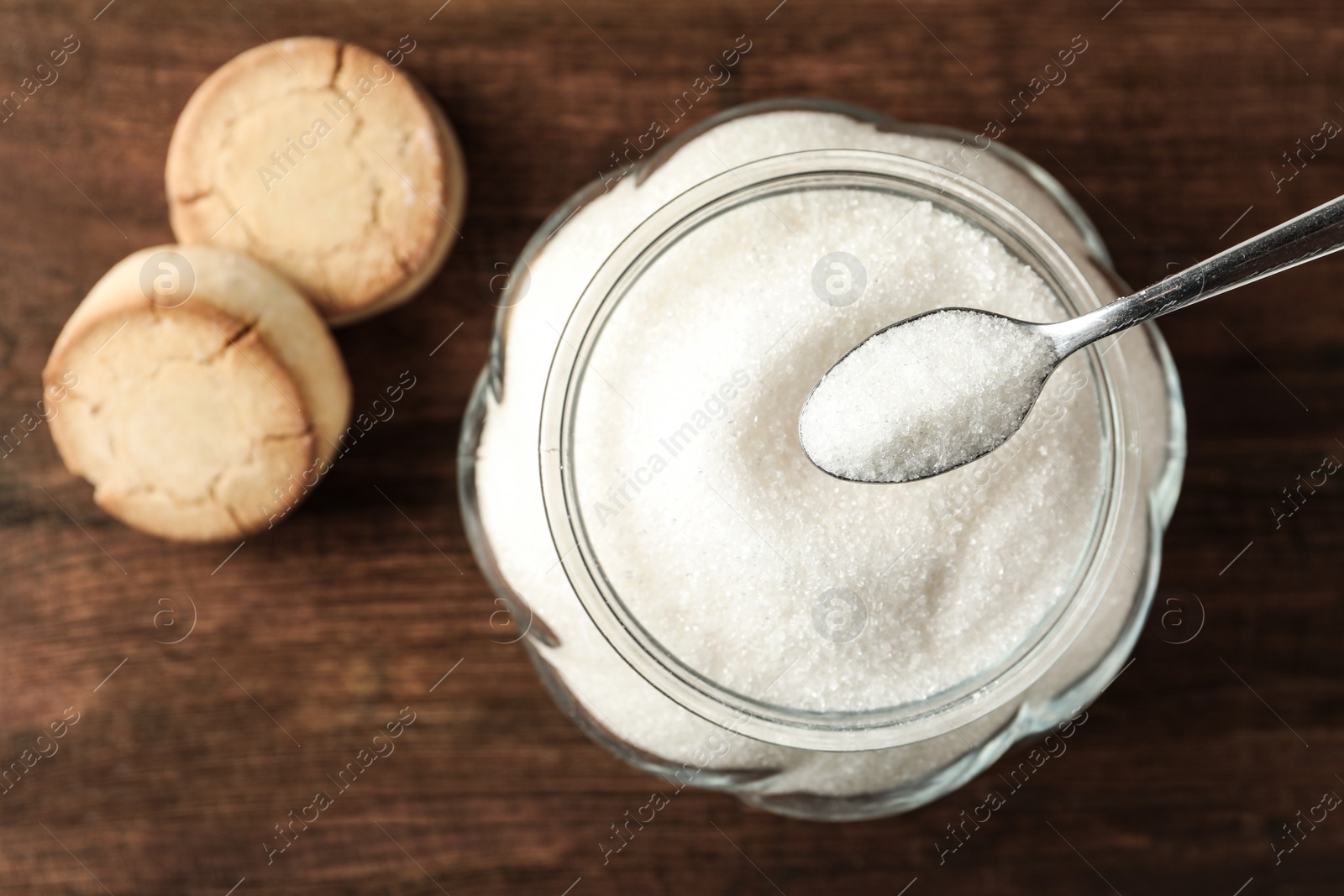 Photo of Glass bowl with sugar and cookies on wooden table, flat lay