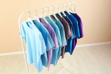 Men's clothes hanging on wardrobe rack against light background